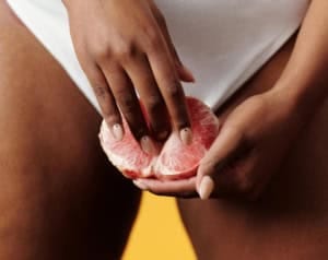 mão brincando com uma tangerina representando dia da masturbação