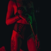 Mulher em pé segurando um chicote em um cenário de sadismo