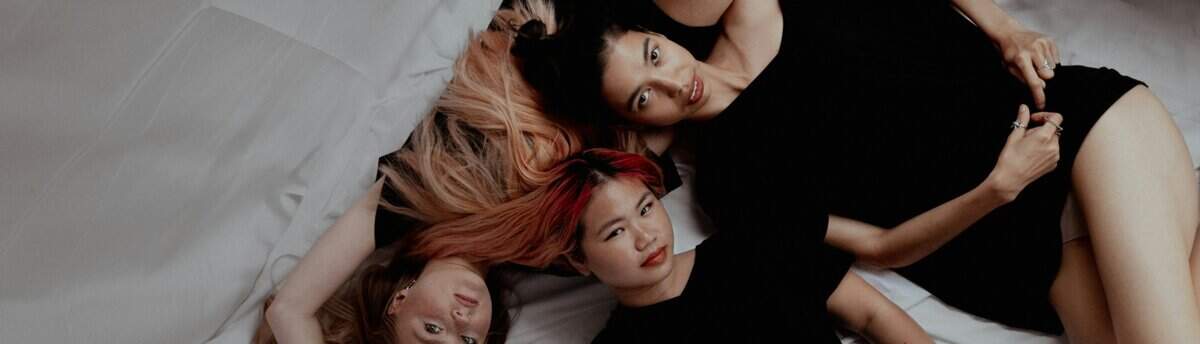 Três mulheres na cama querendo fazer sexo a três